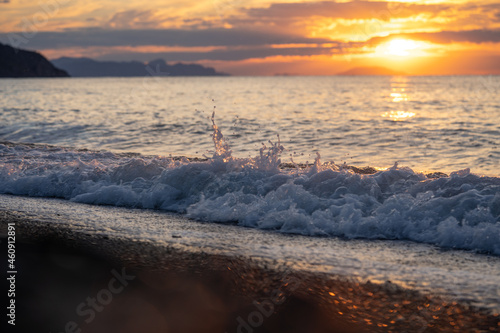 Amazing sunrise over the tropical beach. Yellow sun over sea. Orange colors waves. Nature background. Beautiful serene scene. Morning. Sunlight reflect on water surface