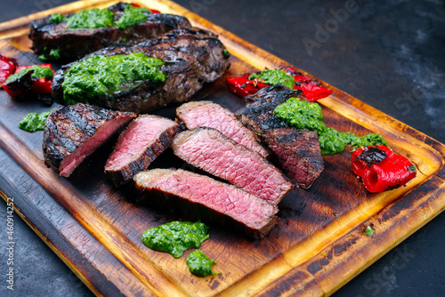 Traditional barbecue dry aged wagyu Brazilian picanha beef steaks served with chili and chimichurri sauce as close-up on a rustic wooden board photo