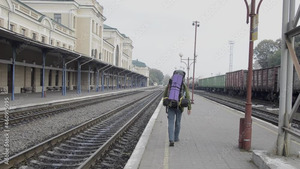 Man on the railway station is going hike with backpack. Journey scene Man on the railway station is going hike with backpack. Journey scene