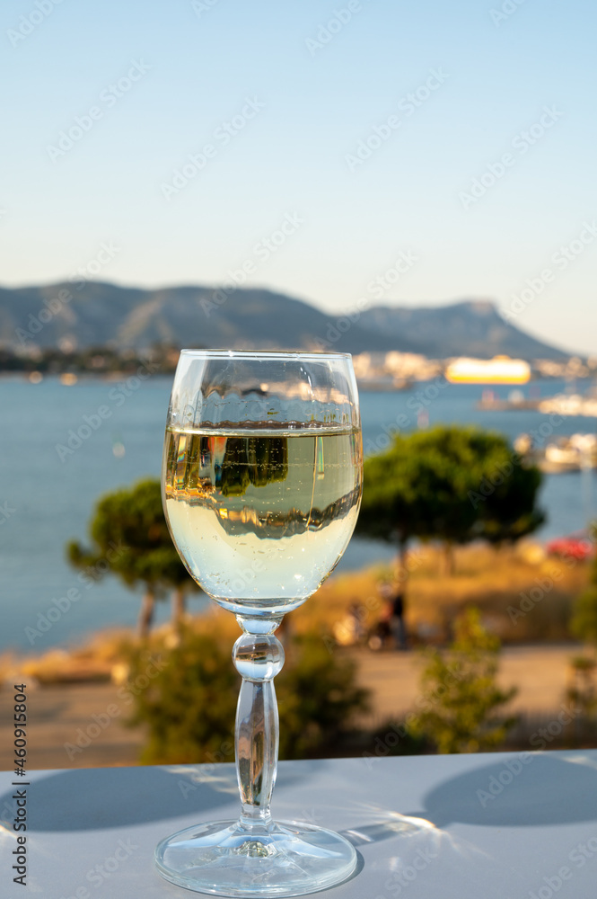 Obraz premium Summer on French Riviera, drinking cold white wine from Cotes de Provence on outdoor terrase with view on harbour of Toulon, Var, France
