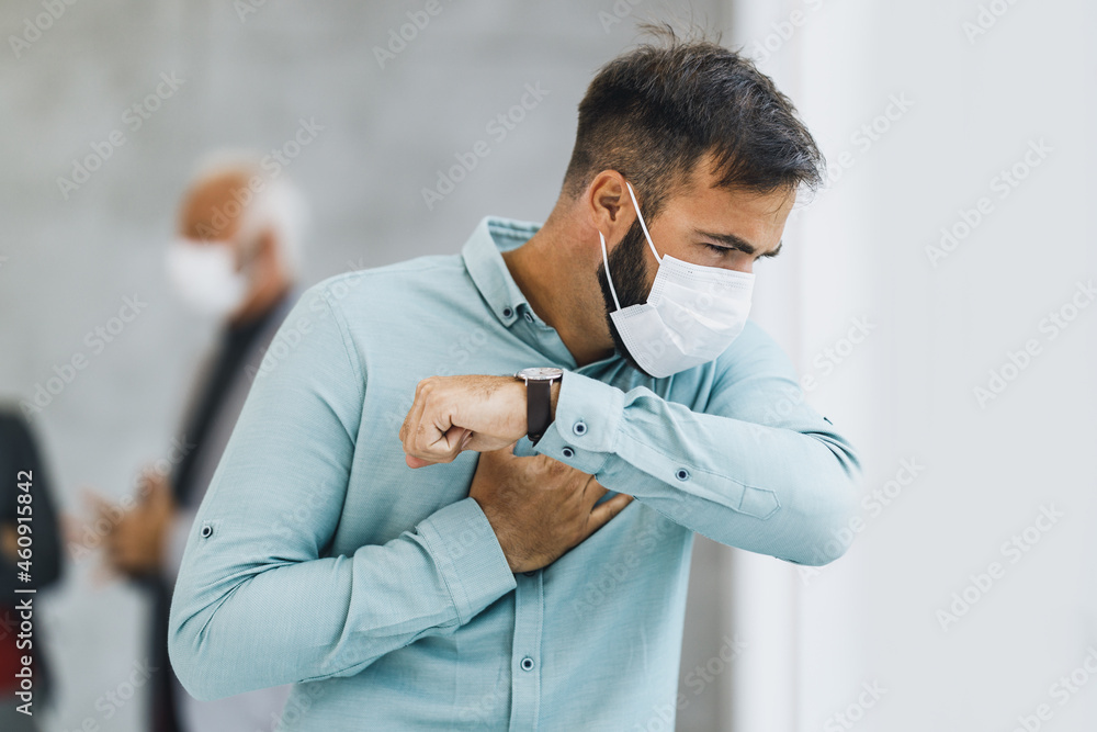 A Business Man With Protective Mask Coughs At The Elbow During Coronavirus Pandemic A Business Man With Protective Mask Coughs At The Elbow During Coronavirus Pandemic