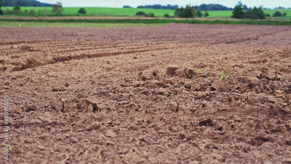 Plowed Brown Soil Field with Green Hills in Background Plowed Brown Soil Field with Green Hills in Background