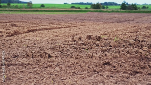 Plowed Brown Soil Field with Green Hills in Background