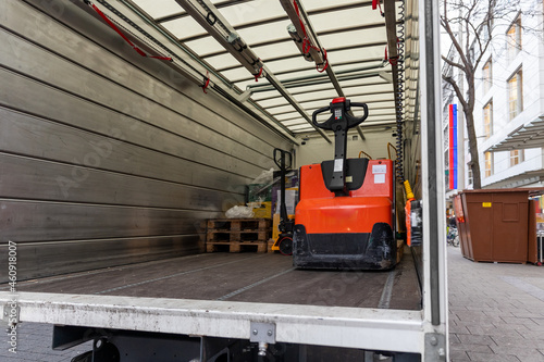 Small white mid size cargo truck parked for unloading open tailgate with little forklift at european city street road. Fast express courier delivery service concept. Shipping logistic distribution © Kirill Gorlov