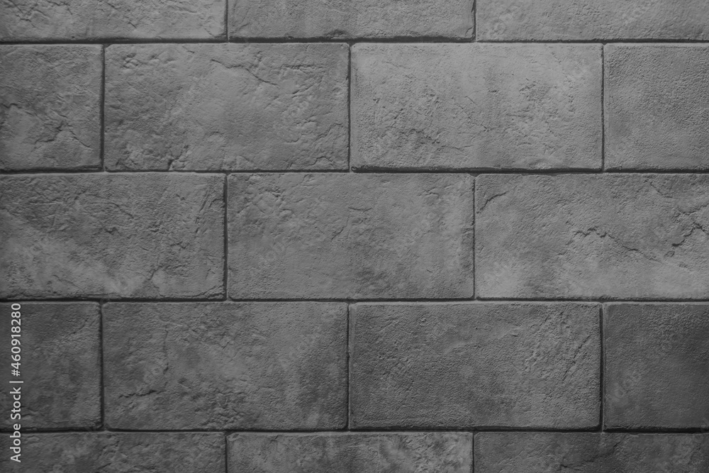 Naklejka premium The wall is made of dark gray stone blocks with scuffs and damage. Dark gray background with brick texture. 
