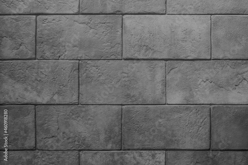 The wall is made of dark gray stone blocks with scuffs and damage. Dark gray background with brick texture. 