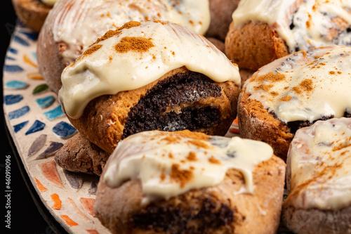 Poppy seeds buns on the ceramic plate on the black background