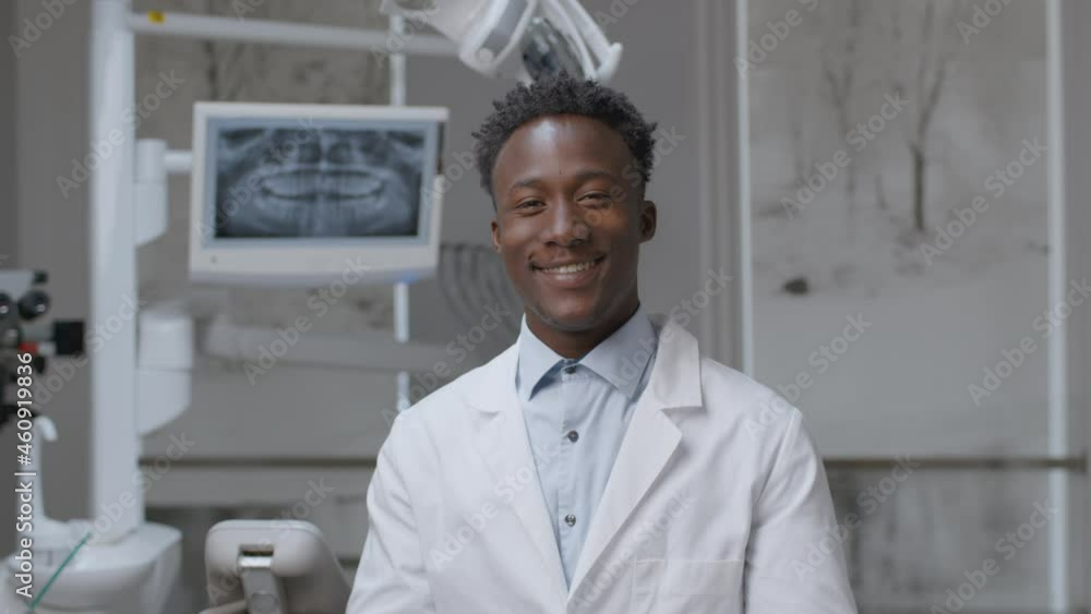 Professional african american male doctor dentist taking off protective eyehlasses and smiling widely to camera Professional african american male doctor dentist taking off protective eyehlasses and smiling widely to camera