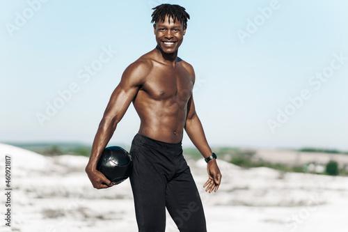 African American crossfit man, fitness man holding abdominal workout ball, outdoors