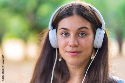 Pretty young woman listening to music in an oak forest.