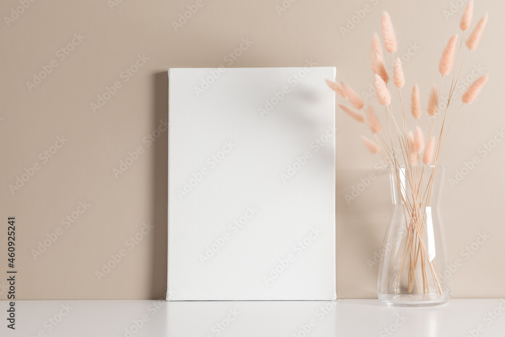 White canvas mockup with dry lagurus on beige wall background. Front view