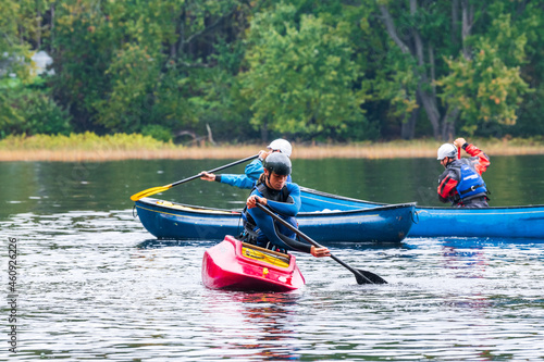 Three canoeists practice paddle strokes on a rainy fall day during a “moving water” paddling course. At Palmer Rapids on the Madawaska River an iconic paddling destination in Eastern Ontario, Canada