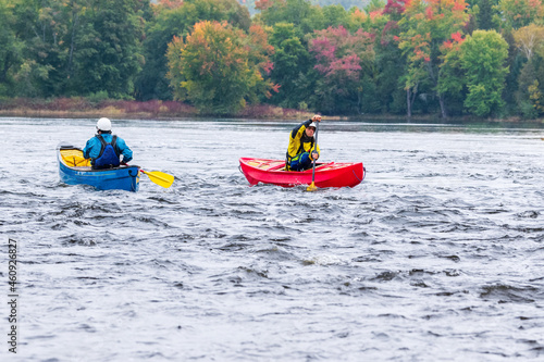 Two canoeists practice paddle strokes on a rainy fall day during a “moving water” paddling course. At Palmer Rapids on the Madawaska River an iconic paddling destination in Eastern Ontario, Canada