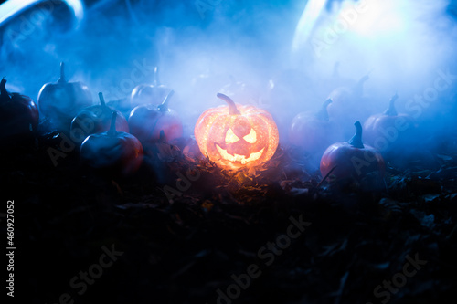 halloween jack-o-lantern on autumn leaves. Scary Halloween Pumpkin looking through the smoke. Glowing 