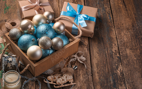 Golden and blue Christmas balls to a box on a wooden background. Side view, copy space.