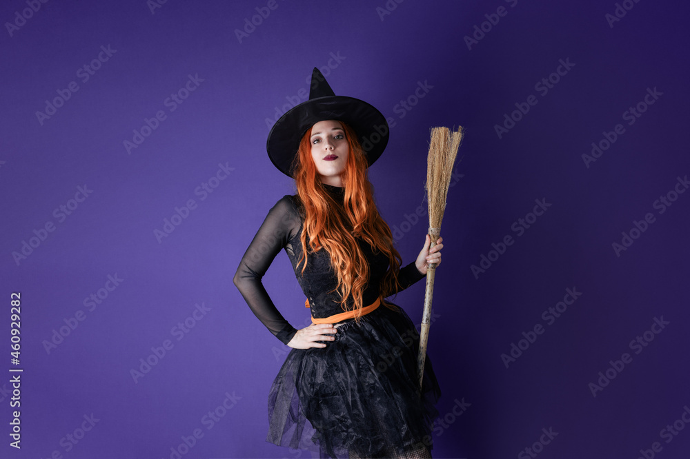 GIRL DRESSED AS A WITCH POSING ON PURPLE BACKGROUND. HALLOWEEN GIRL DRESSED AS A WITCH POSING ON PURPLE BACKGROUND. HALLOWEEN