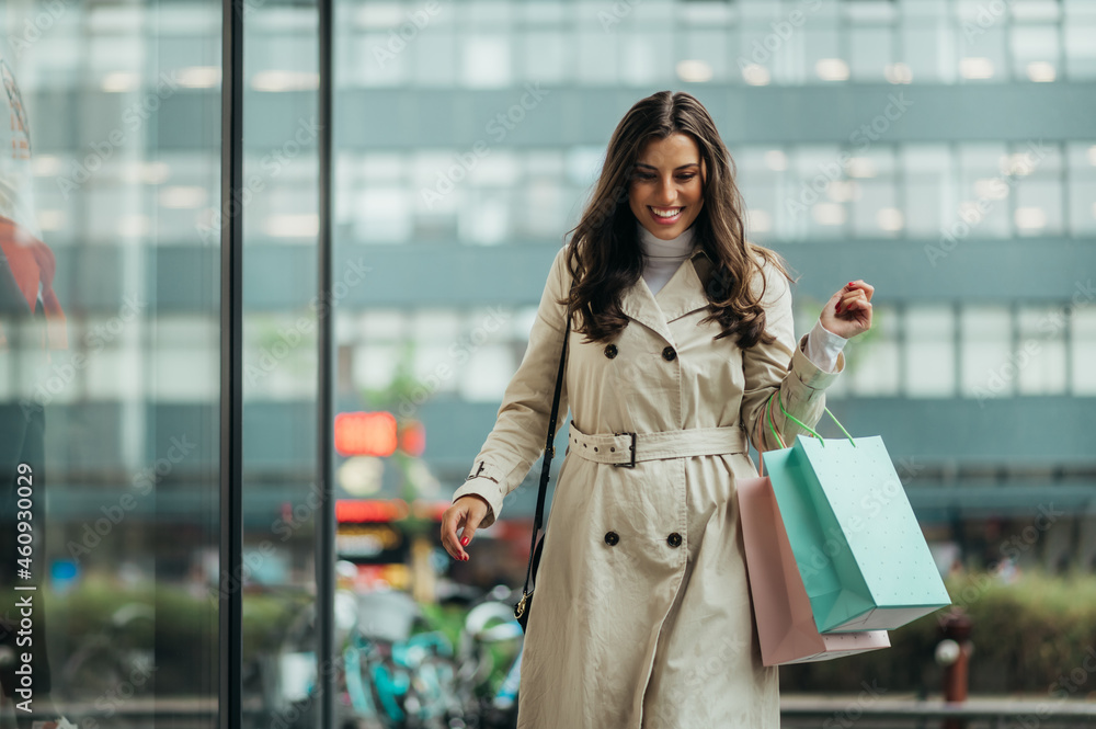 Obraz premium Young beautiful girl holding shopping bags while out in the city