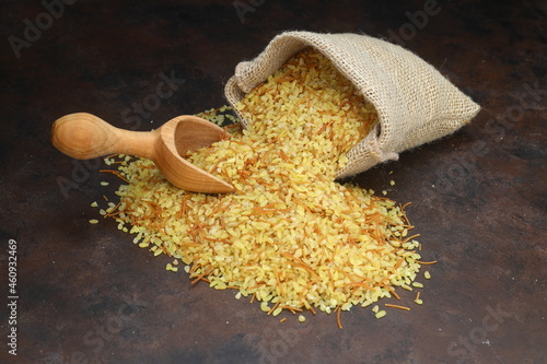 Dry bulgur wheat grains with a spoon close up photo