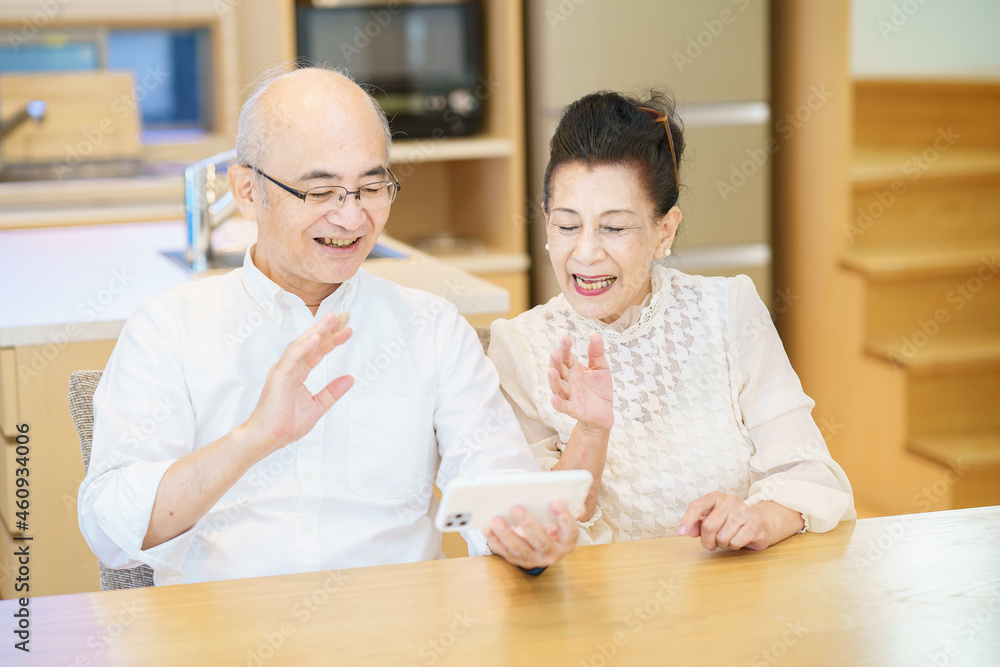 スマートフォンを使って、オンラインコミュニケーションをするシニア夫婦 スマートフォンを使って、オンラインコミュニケーションをするシニア夫婦