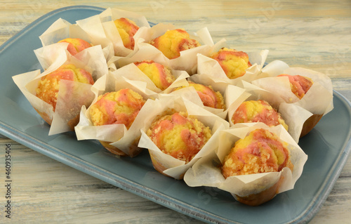 A Dozen lemon strawberry mini muffins in paper cups on blue brunch serving plate