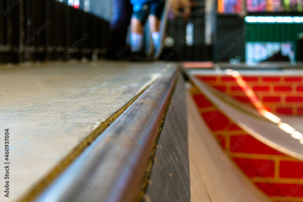 Focus on wooden ramp rail, skate park background.