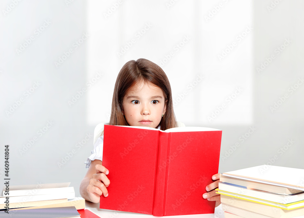 Young cute girl sitting at the table and reading a book Young cute girl sitting at the table and reading a book