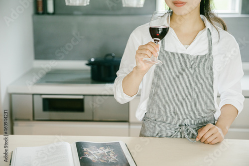 キッチンでワイングラスを持つ女性 キッチンでワインを嗜む女性