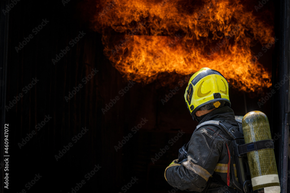 Firefighter in fire fighting operation,Fireman using water and extinguisher to fighting with fire flame in an emergency situation. Firefighter in fire fighting operation,Fireman using water and extinguisher to fighting with fire flame in an emergency situation.