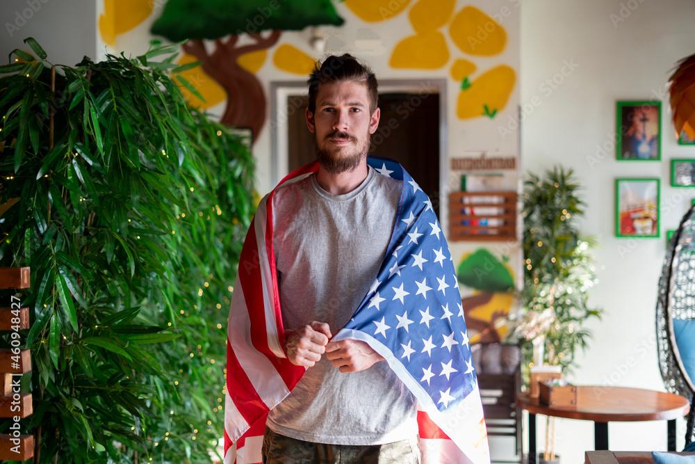 young happy bearded guy covered with usa american flag