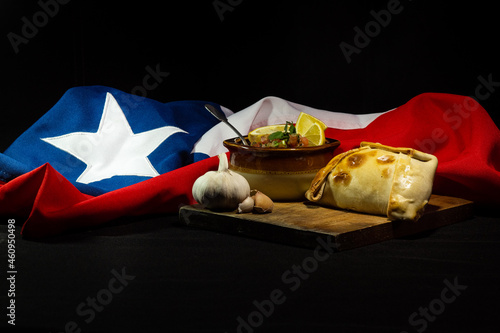 Empanada con pebre y bandera chilena de fondo, comida tradicional de fiestas patrias en chile, 18 de septiembre photo