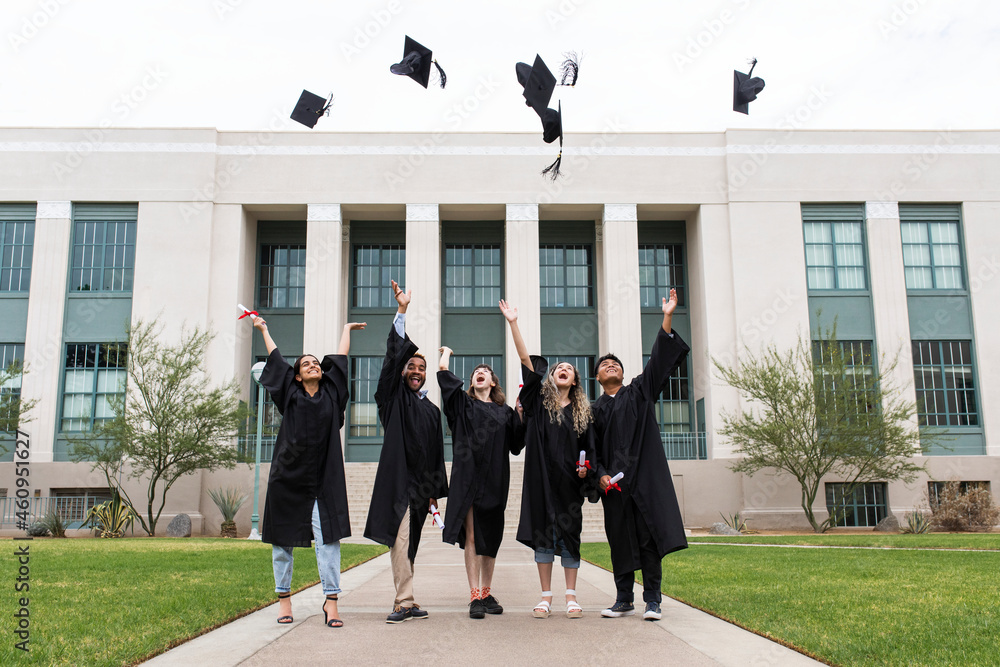 Graduating students throwing graduation caps in the air Stock Photo ...