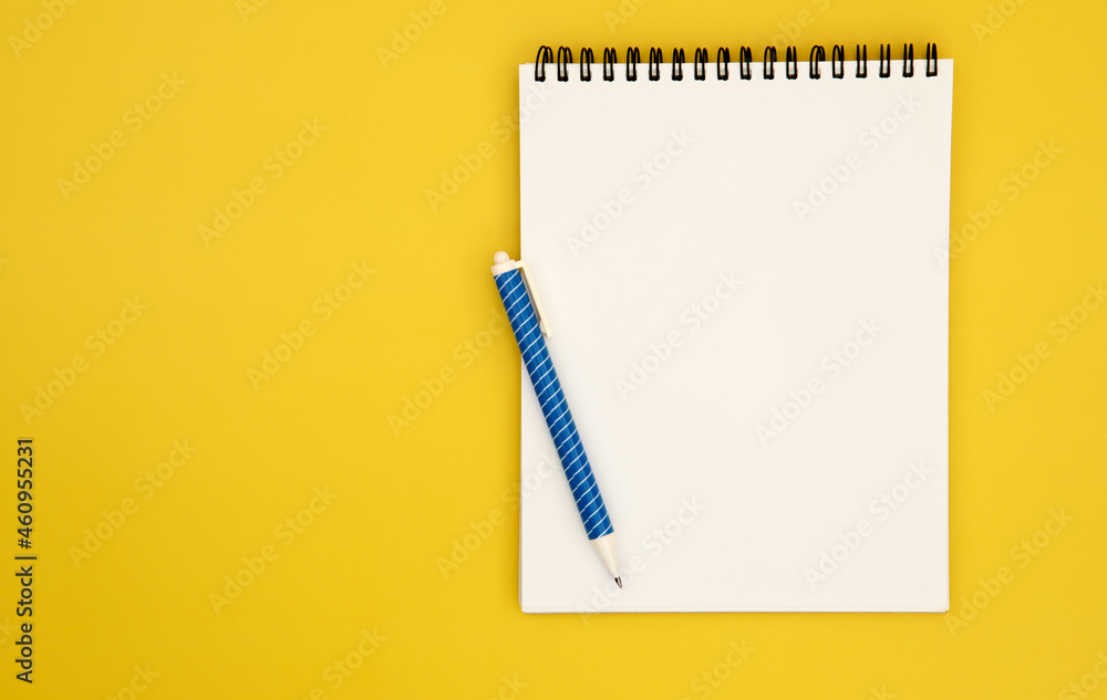 spiral notepad book paper with a blue pen placed on yellow background for creative thinking concept spiral notepad book paper with a blue pen placed on yellow background for creative thinking concept
