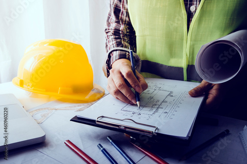 Two colleagues discussing data working and tablet, laptop with on on architectural project at construction site at desk in office