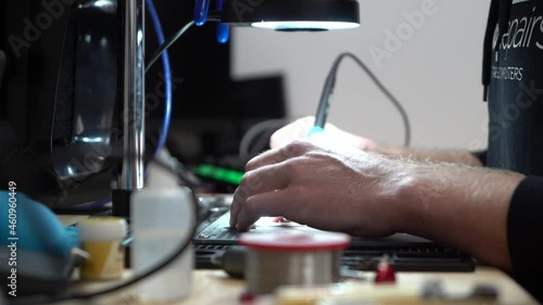 Man fixing up laptop micro soldering under microscope photo