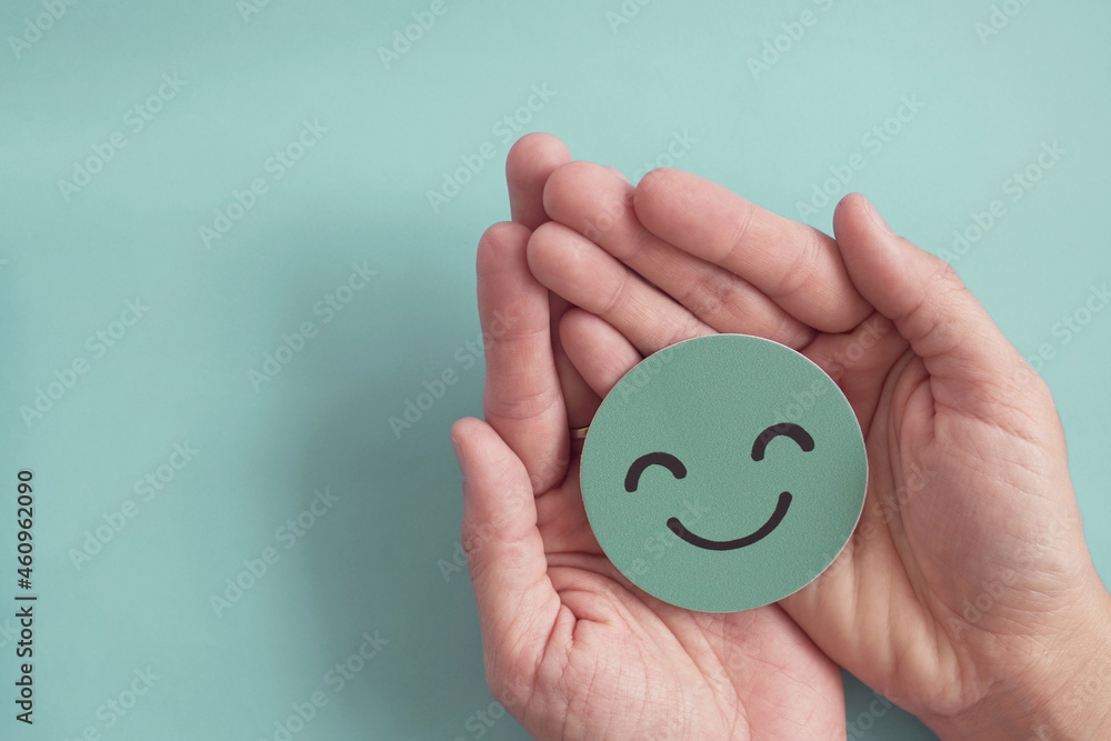 Hands holding green happy smile face paper cut, good feedback rating,positive customer review, experience, satisfaction survey ,mental health assessment, child wellness,world mental health day concept - obrazy, fototapety, plakaty 
