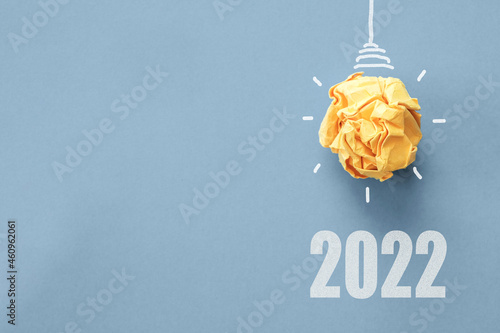 2022 Yellow paper light bulb on blue background, innovative business vision and resolution goal concept
