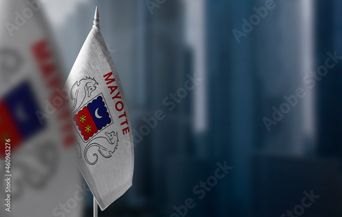 Small flags of Mayotte on a blurry background of the city photo