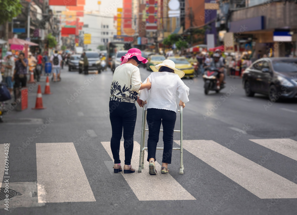 Daughter take care elderly woman crossing the street in Chinatown area