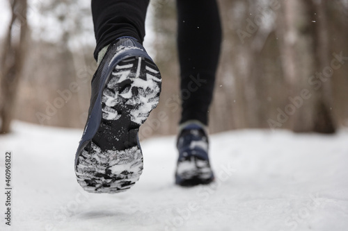 Fotografia Winter exercise fitness lifestyle athlete walking with running shoes on snow and slippery ice needing traction soles on icy sidewalks