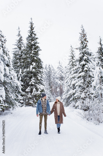full length portrait of happy couple walking in winter forest.