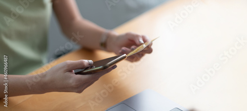 Close up hand of woman using credit card and mobile phone for online shopping and internet payment via mobile banking app.