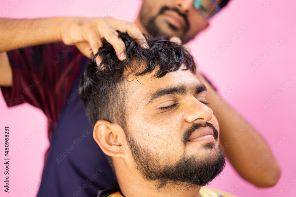 Obraz premium Customer at barber shop enjoying head massage from barber - concept of relaxation and alternative health treatment