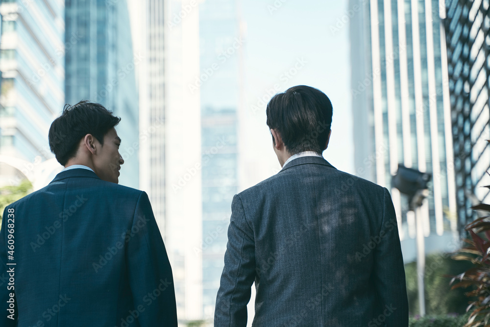 two asian business men walking on downtown street in modern city two asian business men walking on downtown street in modern city