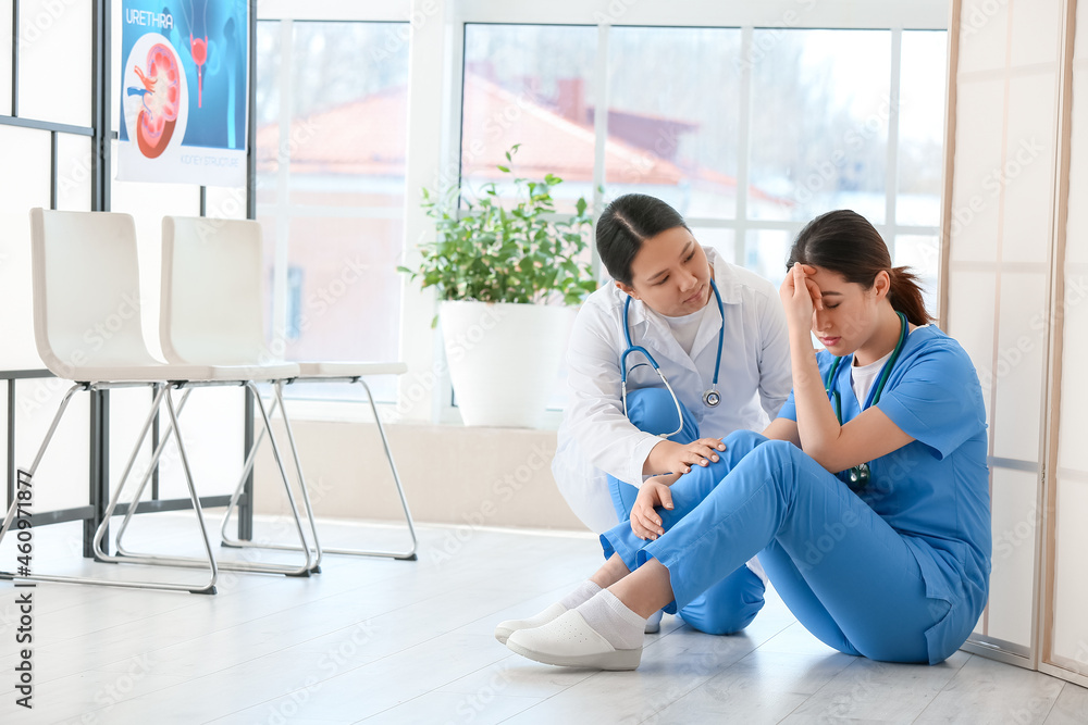 Female Asian doctor calming her colleague in clinic Female Asian doctor calming her colleague in clinic