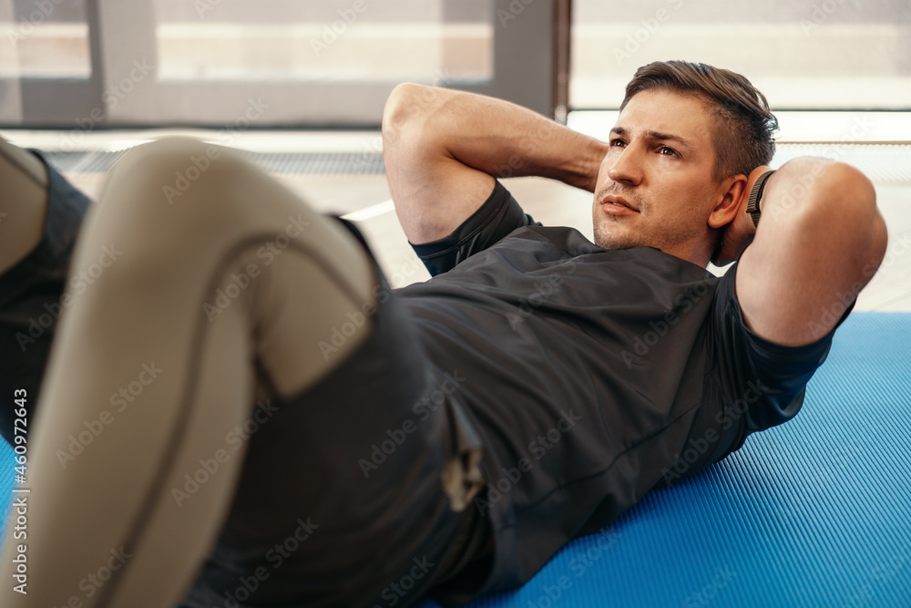 Young muscular caucasian handsome man doing abs exercises on mat Young muscular caucasian handsome man doing abs exercises on mat