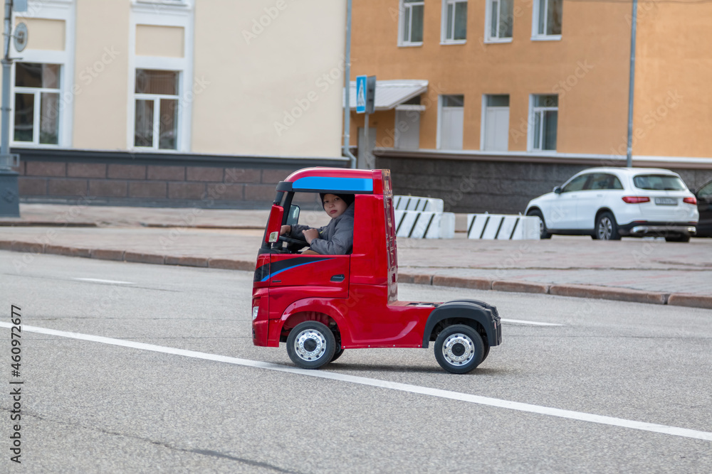 Little cheerful boy rides a red truck.