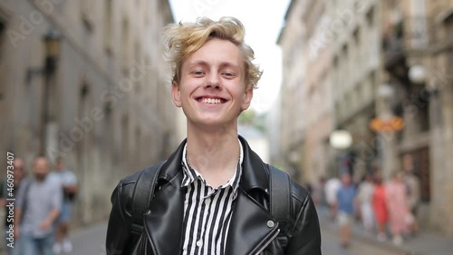 the blond stands on the street and touches the hand of his hair. the guy feels happy photo