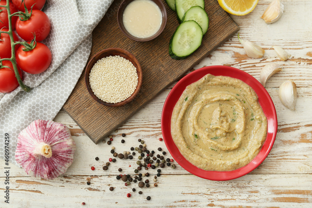 Fototapeta premium Bowl with tasty baba ghanoush, spices and vegetables on white wooden background