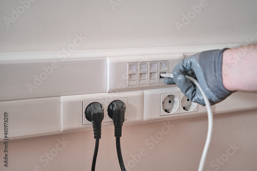 Connection to a computer network in the office, a gloved hand holds a cord for connecting to an Internet outlet photo