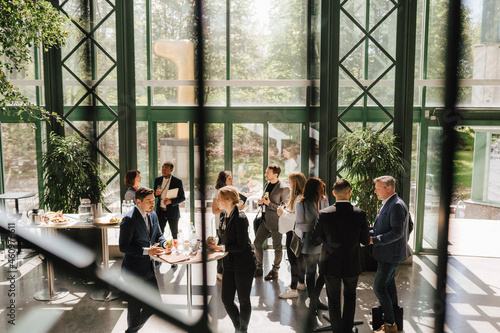 Businessmen and businesswomen discussing while standing around tables at convention center photo